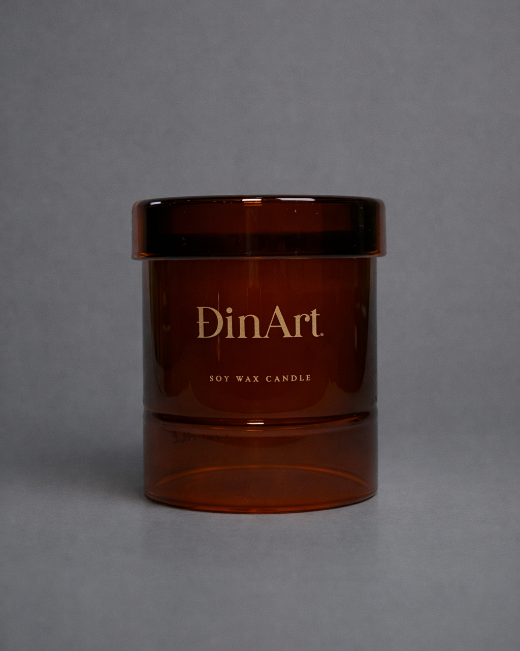 Brown candle jar with 'DinArt' branding on a gray background